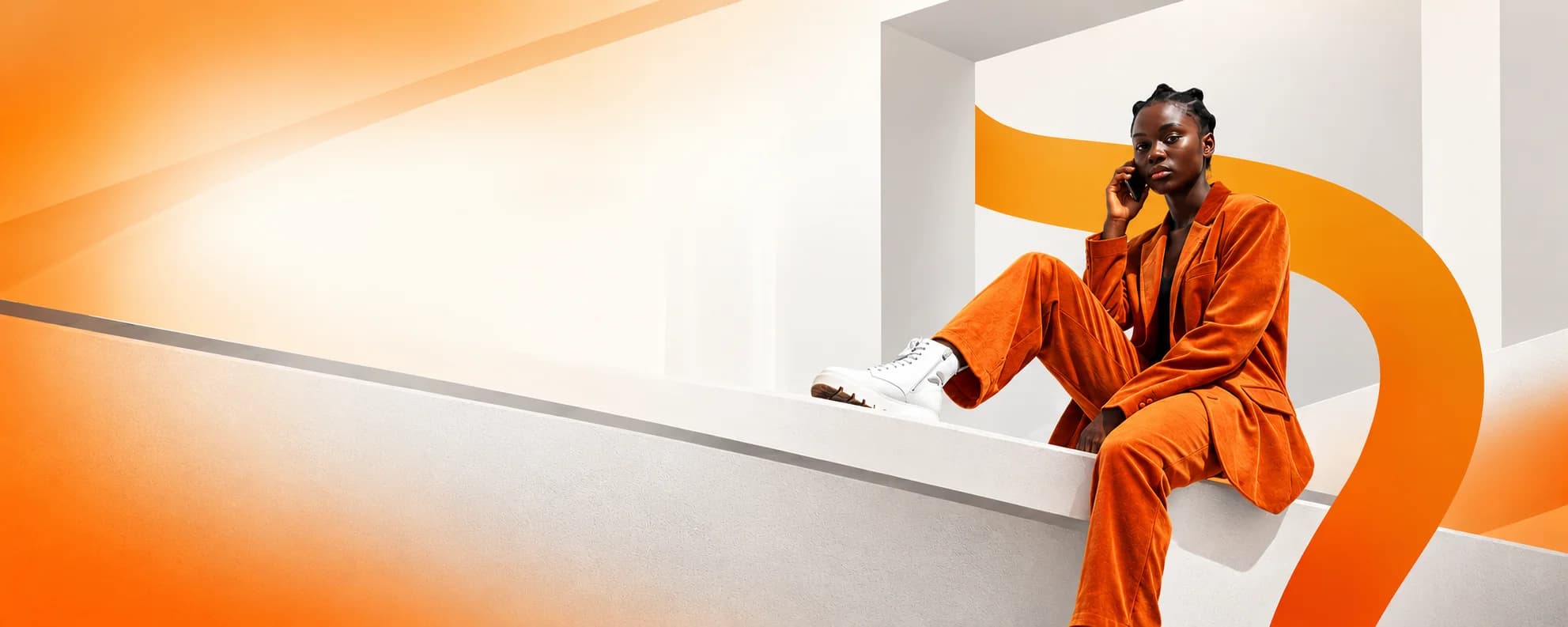 Fashion professional in an orange outfit speaking on the phone in an architectural setting