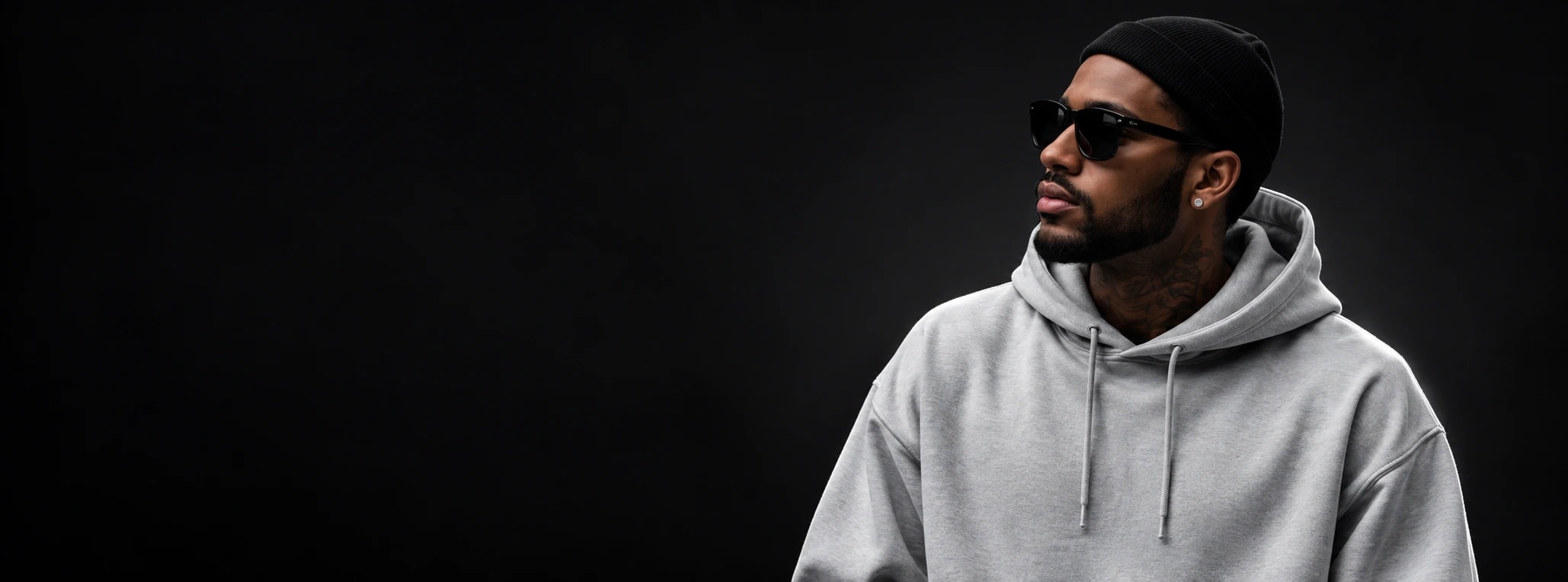 Model wearing a grey oversized hoodie against a black backdrop